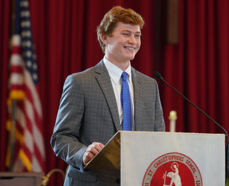 teen student at a podium speaking dressed in a suit and tie